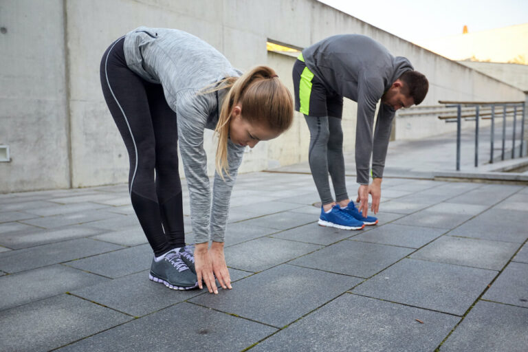 couple stretching and bending forward on street