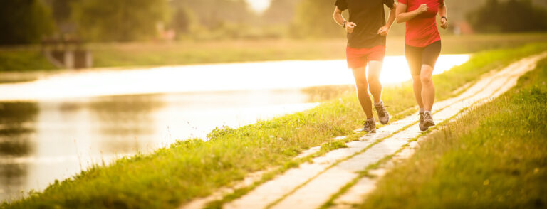 Couple running outdoors, at sunset, by a river, staying active and fit
